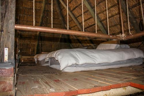 a bed in a straw hut with a mattress at The Ancient Copper Shed in Potchefstroom