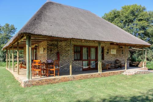 a hut with a grass roof on a field at The Ancient Copper Shed in Potchefstroom