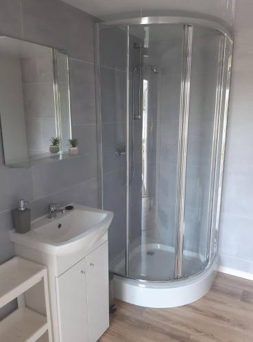 a white bathroom with a shower and a sink at Domki na Mazurach "Malinka" in Suchy Róg