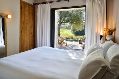 a bedroom with a large bed and a large window at Domaine de Peretti della Rocca in Figari
