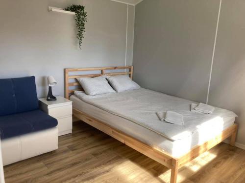 a bedroom with a bed and a blue chair at Domki na Mazurach "Malinka" in Suchy Róg