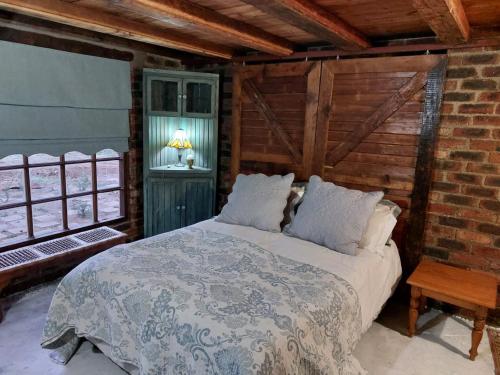 a bedroom with a bed and a brick wall at The Ancient Copper Shed in Potchefstroom