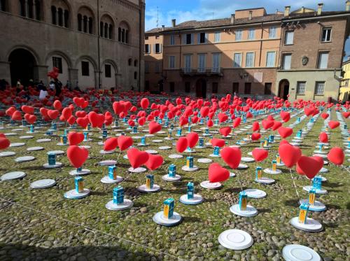 a large group of red hats and plates on the grass at Parmigianino Nove in Parma