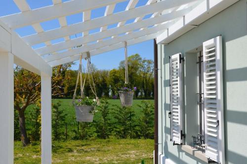 eine Pergola mit zwei Blumentöpfen, die von einem Haus hängen in der Unterkunft B&B Le Col-vert in Lido di Dante