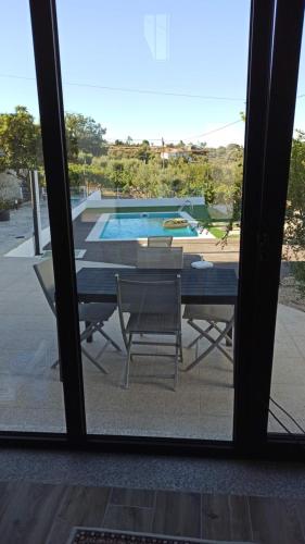 a table and chairs with a view of a swimming pool at Casa do Chão do Cruzeiro in Arcozelo