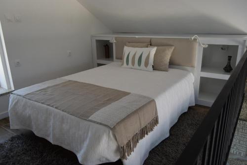 Un dormitorio con una gran cama blanca con almohadas. en Casa do Chão do Cruzeiro, en Arcozelo