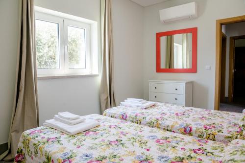 two beds in a room with a mirror and two windows at Casas da Estação in Marvão