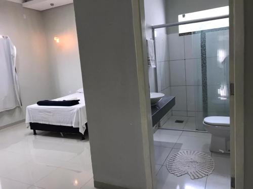 y baño con cama, aseo y lavamanos. en Casa ampla e confortável próximo ao centro en Corumbá