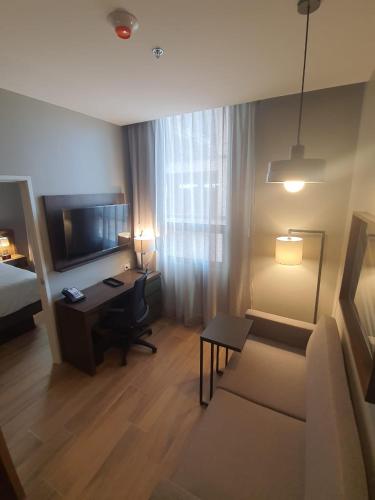 a living room with a couch and a desk in a hotel room at Staybridge Suites - Guadalajara Novena by IHG in Guadalajara