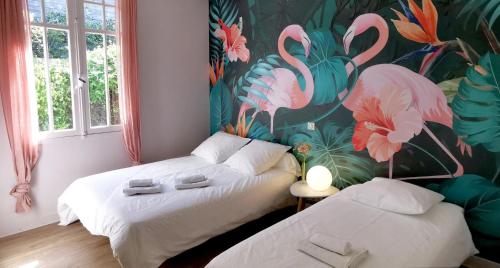 two beds in a room with a mural of flamingos at Les Embruns in Mimizan-Plage