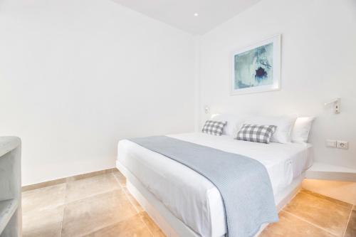 a white bedroom with a white bed and a tv at Pelican Paros in Parikia