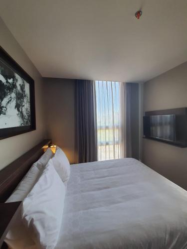 a bedroom with a large white bed with a window at Staybridge Suites - Guadalajara Novena by IHG in Guadalajara