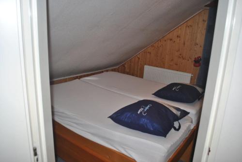 ein kleines Bett mit zwei blauen Kissen darauf in der Unterkunft Snoepie in Víchová nad Jizerou