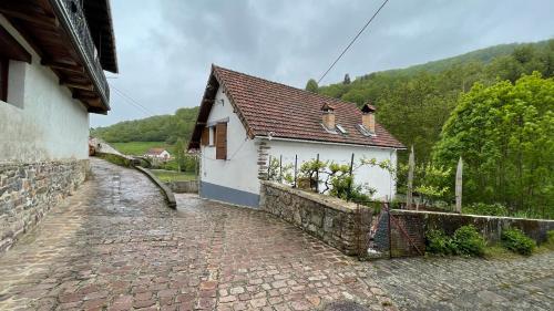 a small white house with a brick road next to a building at La Borda del Tío Nicolás - Selva de Irati in Aribe
