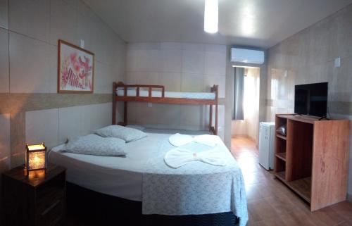 a bedroom with a bed and a tv and a bed sidx sidx sidx at Hotel Ferrugem Eco Village in Garopaba