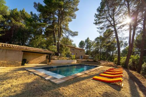 a swimming pool with lounge chairs next to a house at Stunning panoramic views and heated pool in Roussillon in Roussillon