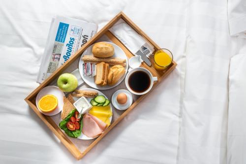 a tray of breakfast foods and coffee on a bed at DAYS City Suites in Patra