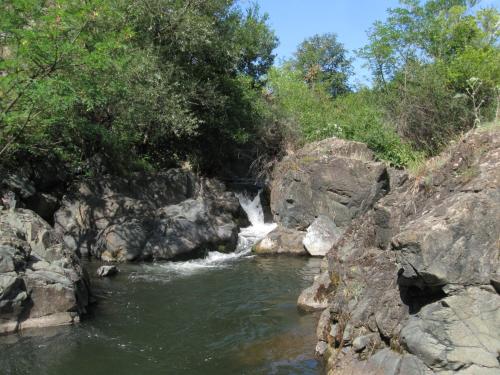a river with a waterfall in the middle of rocks at Ethno Village Bogut in Bogutovac