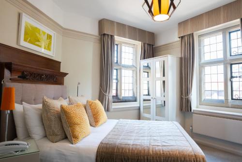 a bedroom with a bed with pillows and windows at Fanhams Hall, Exclusive Collection in Ware