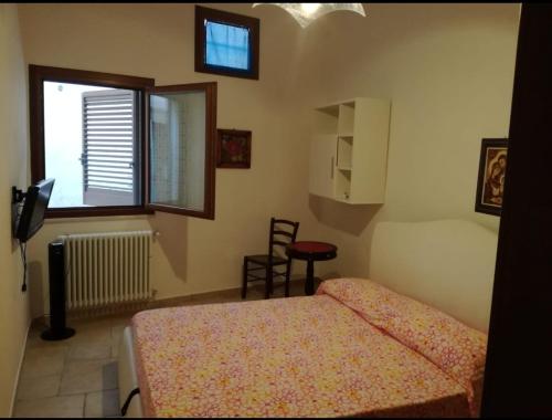 ein Schlafzimmer mit einem Bett, einem Fenster und einem Stuhl in der Unterkunft Casa la Corte in Parabita