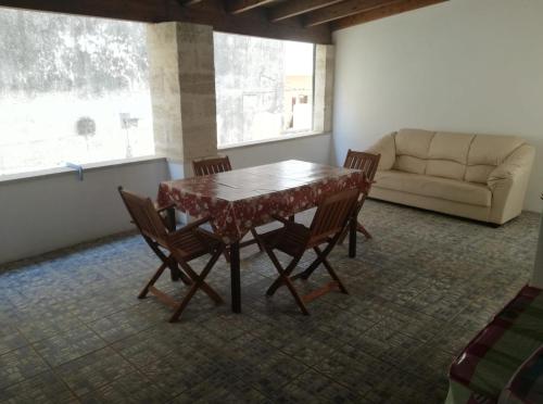 een tafel en stoelen in een woonkamer met een bank bij Casa la Corte in Parabita