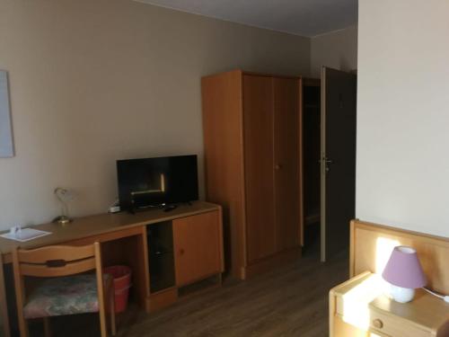 Zimmer mit einem Schreibtisch, einem TV und einem Schrank in der Unterkunft Hotel Waldidyll in Eggesin