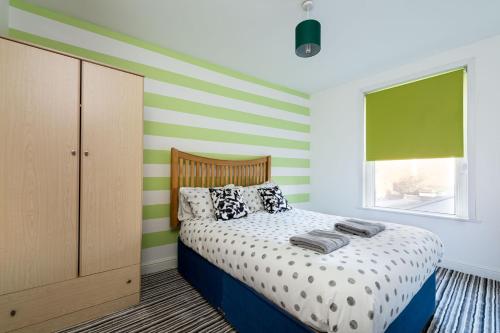 Schlafzimmer mit einem Bett mit Grün- und Weißstreifen in der Unterkunft Hepburn House 4 Bedroom Property - Stayseekers in Salisbury