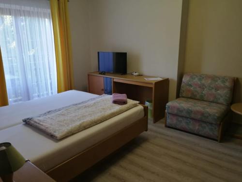 a bedroom with a bed and a chair and a desk at Hotel Waldidyll in Eggesin