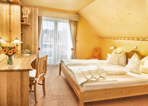 ein Schlafzimmer mit einem großen Bett, einem Schreibtisch und einem Tisch in der Unterkunft Kraners Alpenhof BIO Bed and Breakfast Pension in Weissensee
