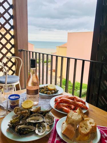 - une table avec 2 assiettes de fruits de mer et une bouteille de vin dans l'établissement Appartement bord de mer Saint Pierre la Mer, à Saint Pierre La Mer