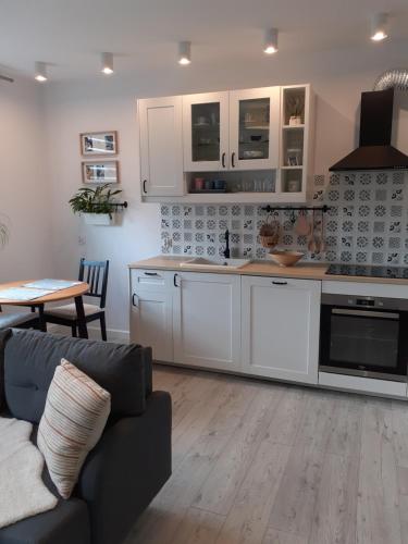a kitchen with white cabinets and a couch and a table at Apartament Villa Natura II in Szczytno