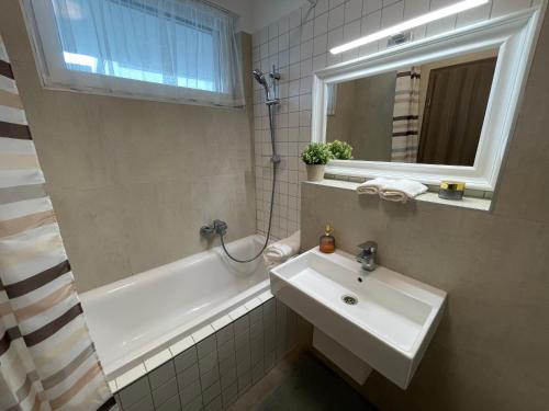 a bathroom with a sink and a tub and a mirror at Vízpart Hullám Apartman in Balatonlelle