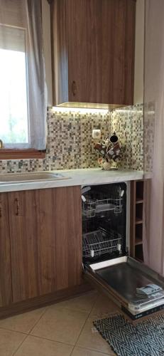 a kitchen with an open dishwasher in a cabinet at Casa Dikella in Mesimvría