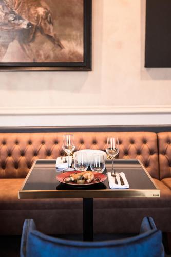 a table with a plate of food and wine glasses at La Maison TATIN in Lamotte-Beuvron
