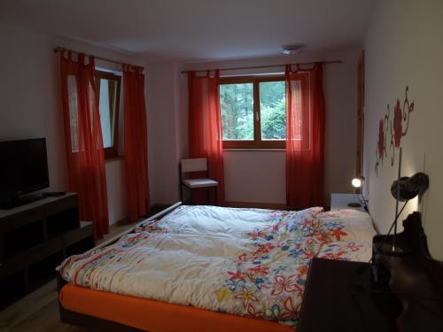 Schlafzimmer mit einem Bett, roten Vorhängen und einem TV in der Unterkunft B&B Casa Moni in Bosco/Gurin
