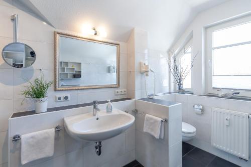 een witte badkamer met een wastafel en een spiegel bij Am Horizont No 1 Fewo für 4 Pers, 2 Schlafzimmer, W-LAN, Homeoffice-geeignet, Kamin, Parkplatz in Zingst
