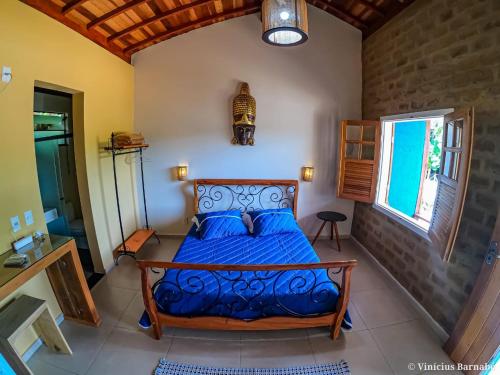 a bedroom with a bed with blue sheets and a window at Pousada Vila Mandalah in Carrancas