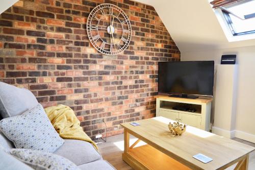 a living room with a brick wall and a tv at Bakers Cottage in Ironbridge