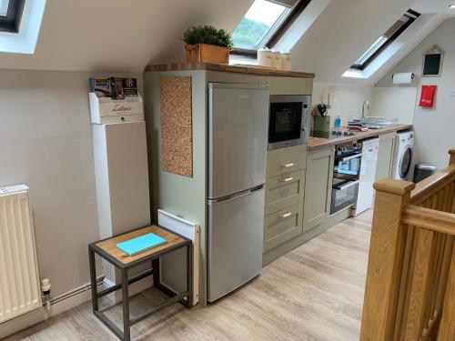 eine Küche mit einem Kühlschrank und einem Tisch darin in der Unterkunft Bakers Cottage in Ironbridge