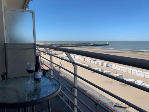 a glass of wine sitting on a table on a balcony overlooking the beach at Beach View Five in Blankenberge