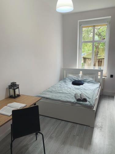 a bedroom with a bed and a table and a window at Rooms4Less in Gdańsk