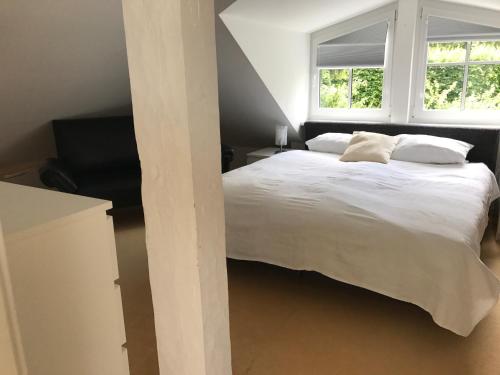 a bedroom with a large white bed with two windows at Maisonette Ferienappartement mit Garten in Donaueschingen