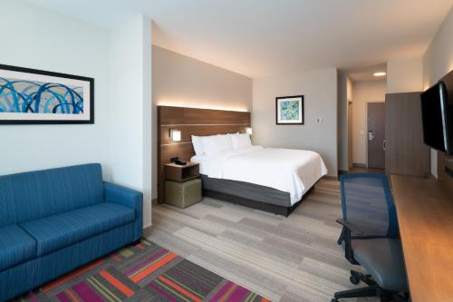a hotel room with a bed and a couch and a tv at Holiday Inn Express & Suites - St Peters by IHG in Saint Peters