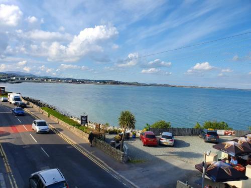 a road with cars parked next to a body of water at Seafront Apartment in Newcastle