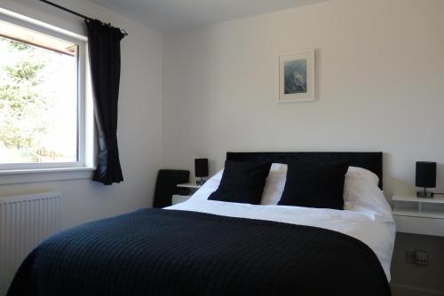 a bedroom with a black and white bed and a window at Tanleys Guesthouse in Grantown on Spey
