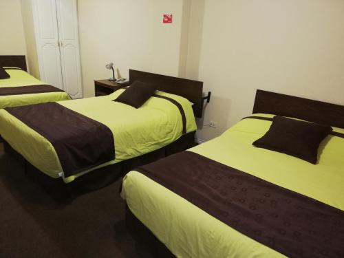 a bedroom with two beds with yellow and brown sheets at Hotel Bonaventure in Quito