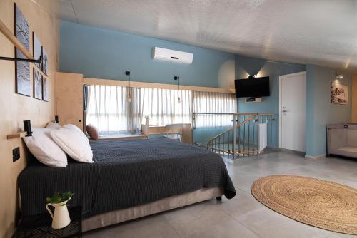 1 dormitorio con cama y pared azul en Bar-On Vacation Resort - Nature, Culture, Tours & Tastes near Nahariyya - בר-און ריזורט, בתי מפונים , טבע, תרבות, סיורים וקולינריה, en Ben ‘Ammi