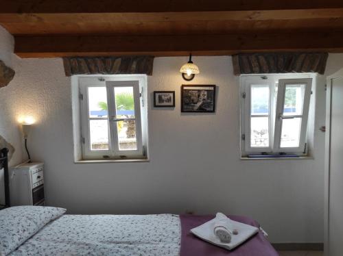 a bedroom with two windows and a bed at Apartment Valun 60 in Valun