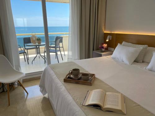 a hotel room with a bed with a book and a balcony at Mediterraneo Sitges in Sitges