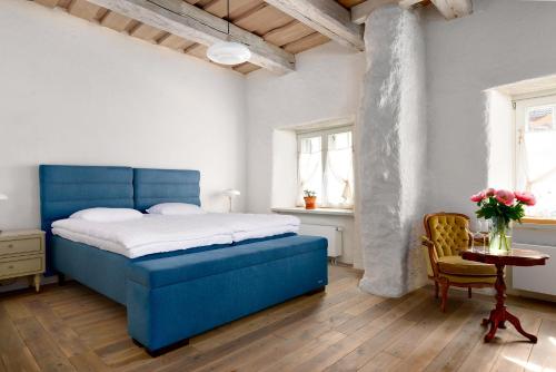 a bedroom with a blue bed and a table at Nurmuižas viesnīca in Lauciene